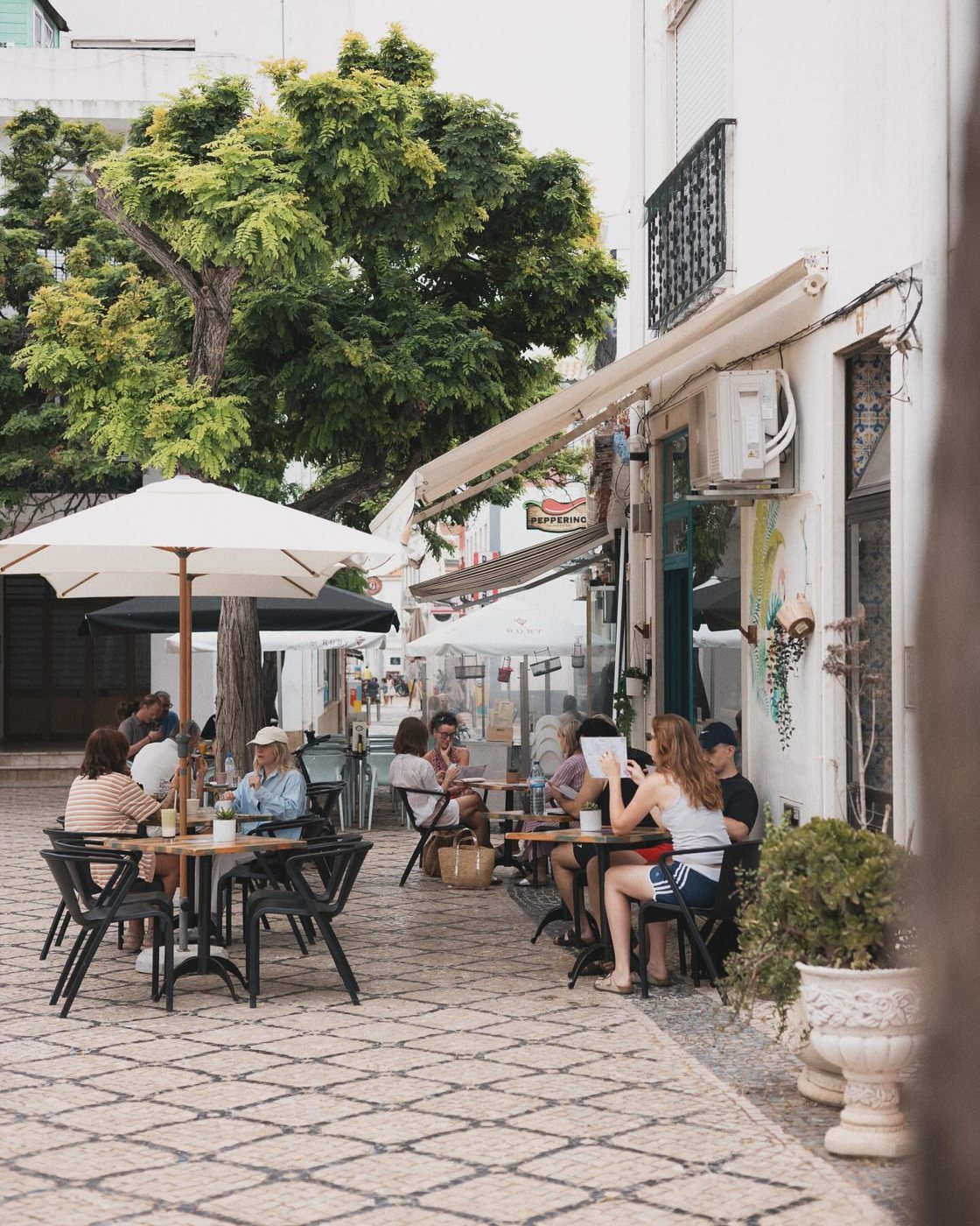 Esplanada do Goji Lounge Café com chapéus-de-sol numa rua de calçada em Lagos